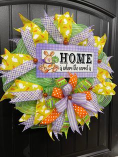 a colorful wreath with the words home is where the bunny is hanging on a door