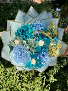 a bouquet of blue and yellow flowers on top of green plants in a garden with butterflies