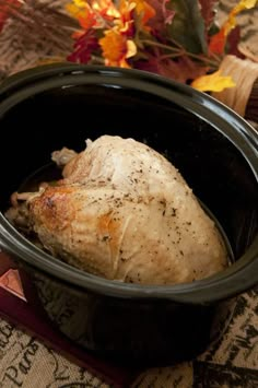 a cooked chicken in a crock pot with autumn leaves and pumpkins behind it