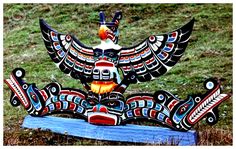 a bird statue sitting on top of a wooden block in the grass with an eagle painted on it's body