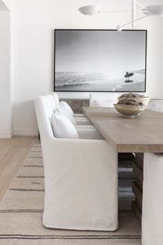 a dining room table with two white chairs and a bowl on top of the table