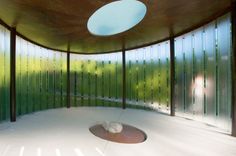 an empty room with lots of glass walls and a round light fixture on the ceiling