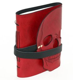 a red leather book with a skull on the cover and a black strap around it