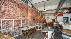 an empty restaurant with brick walls and tables