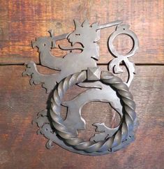 a metal wall hanging on the side of a wooden building with a dragon and rope around it