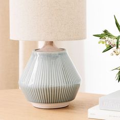 a blue vase sitting on top of a wooden table next to a book and lamp