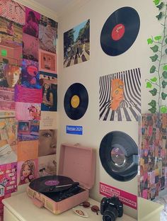 a record player sitting on top of a table next to a wall covered in records