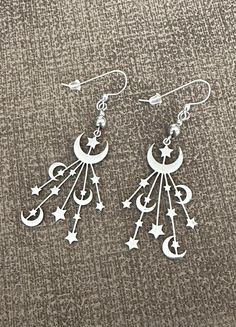 These beautiful and unique handmade earrings feature celestial stainless steel moon and star drops hanging from 5mm stainless steel beads.  Stainless steel means they stay shiny and will not tarnish, rust or discolor.  They are sure to compliment any outfit  These quality earrings are hung on .925 sterling silver earwires. Stoppers are included for secure wear. The total length from the top of the earwire is 2 5/8 inches.   Please view the model shot for size reference on an adult.  I offer a wi Celestial Sterling Silver Earrings, Celestial Dangle Earrings With Moon Charm, Celestial Moon Earrings With Star Charm, Bohemian Star-shaped Earrings With Moon Charm, Celestial Moon-shaped Earrings With Star Charm, Unique Handmade Earrings, Moon And Star Earrings, Artisan Necklace, Stainless Steel Earrings