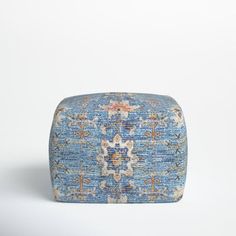 a blue and beige ottoman with an intricate design on the top, in front of a white background