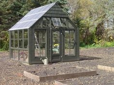 a small green house sitting on top of a dirt field