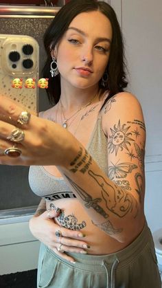 a woman taking a selfie with her cell phone and tattoos on her arm while standing in front of a mirror