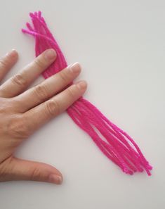 a person's hand with pink thread on the top of their palm and fingers