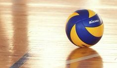 a blue and yellow volleyball sitting on top of a hard wood floor