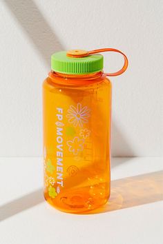 an orange water bottle with a green lid on a white table next to a wall