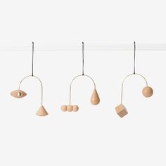 four wooden ornaments hanging from a line on a white wall with no one in the photo