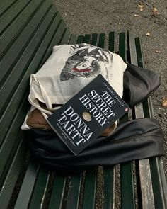 two books sitting on top of a green park bench next to a white t - shirt