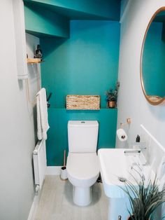 a white toilet sitting next to a sink in a bathroom under a blue painted wall