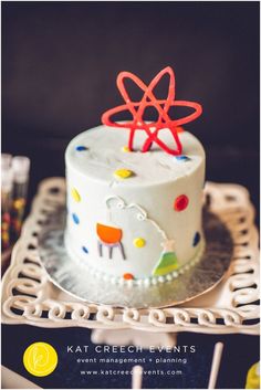 a white cake with red icing and an atomic symbol on top