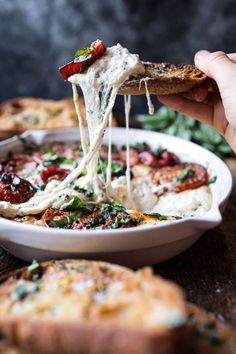 a person is taking a slice of pizza from a white bowl filled with lasagna