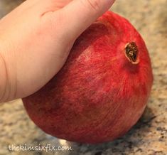 a hand holding an apple on top of a counter