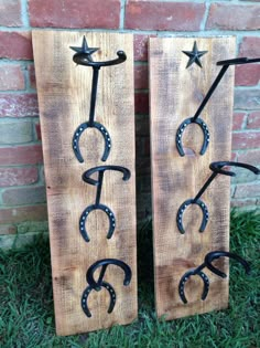 two wooden signs with horseshoes and stars on them sitting in front of a brick wall