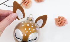 a hand holding a glass ornament with a deer face on it