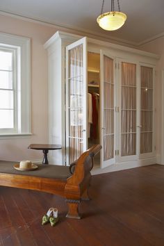 a wooden bench sitting in the middle of a living room next to a white door