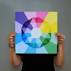 a woman holding up a piece of art with multiple colors