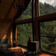 a living room filled with furniture next to a large window covered in forest view windows