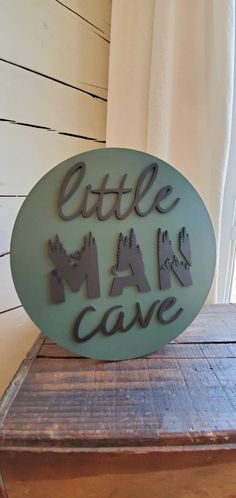 a sign that says little man cave on top of a wooden table next to a window