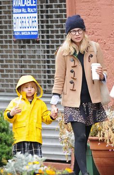 a woman and child holding hands while walking down the street