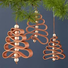 two ornaments hanging from a tree branch with pine cones and beads in the shape of spirals