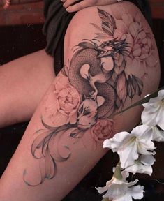 a woman's thigh with flowers and a dragon on it