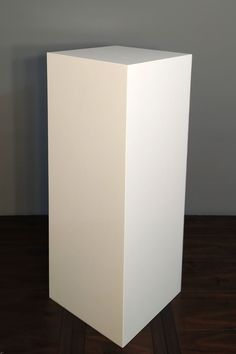 a white square object sitting on top of a wooden floor next to a gray wall