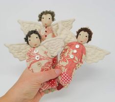 a hand is holding three small angel dolls