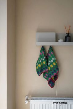 two towels are hanging on the wall next to a radiator and heater