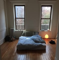 a bed sitting in the middle of a room next to two windows and a radiator