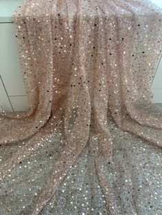 a pink and silver sequinized fabric on top of a white countertop next to a window