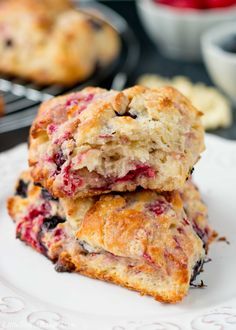 two scones stacked on top of each other on a white plate with fruit in the background