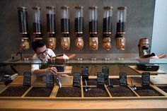 a man is working behind the counter of a coffee roasting station with lots of cups and spoons