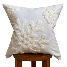 a white pillow sitting on top of a wooden stool next to a chair with a snowflake design on it