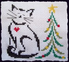 a cross stitched picture of a cat next to a christmas tree