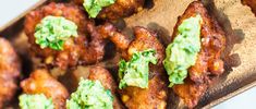 some fried food is sitting on a wooden tray with guacamole toppings