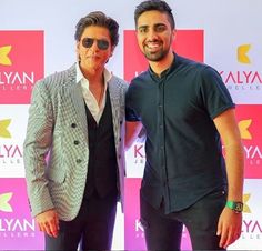 two men standing next to each other on a red carpet