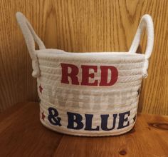 a red, white and blue basket sitting on top of a wooden table next to a wall