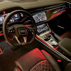 the interior of an audi car with red and black leather trims, steering wheel controls, and dashboard lights