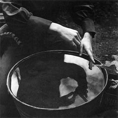 black and white photograph of person holding a large metal bowl with one hand on it