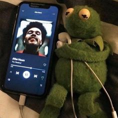 a stuffed animal sitting next to a cell phone with the image of a man on it