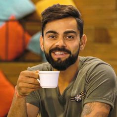 a man with a beard is holding a coffee cup in front of him and smiling at the camera