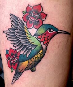 a colorful hummingbird with flowers on its back leg tattoo design for men and women